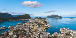 A view of the city of Ålesund, with the ocean surrounding. A bright blue sky on this day.