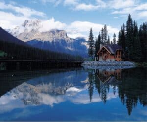 A log cabin near the lake in the mountains, reflecting the sky